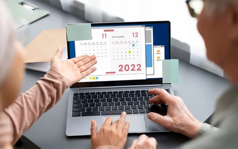 two people looking at a calendar on laptop screen